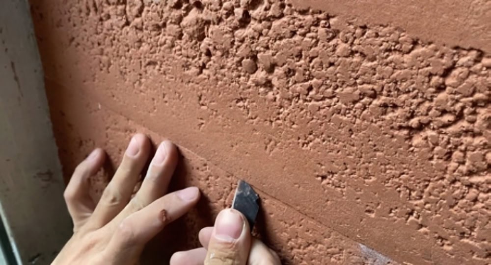 Worker using a blade to cut and adjust Angtai flexible tile edges during installation.